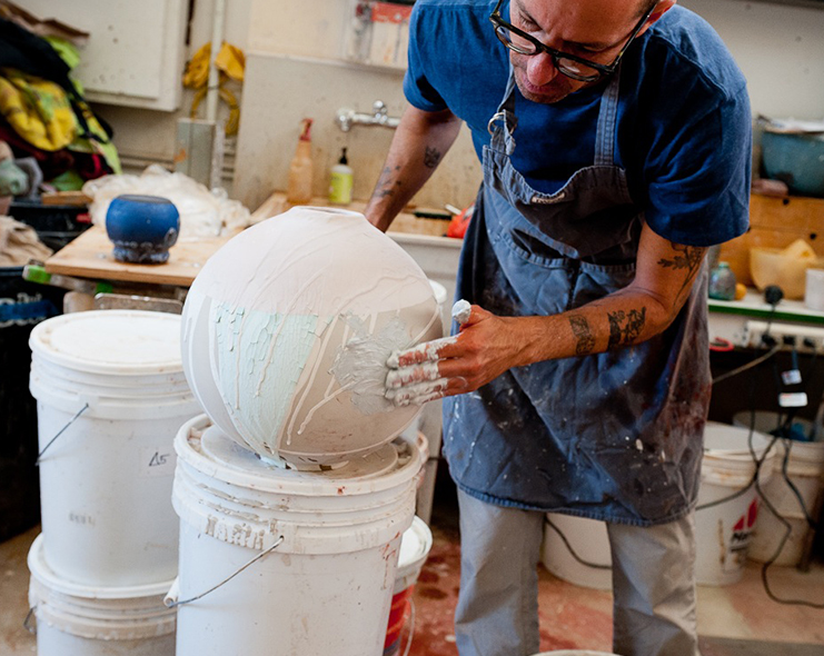 Adam adding glaze to a vase.