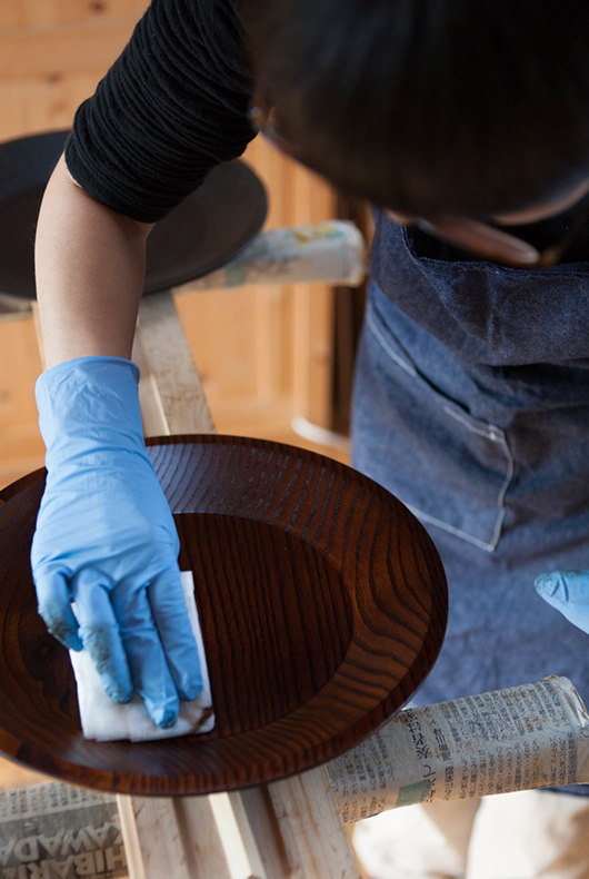Minako touches up the surface of a lacquer dish, after leaving it to dry.