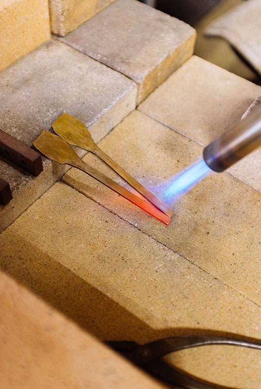 Heating up the brass so she can manipulate it later on.