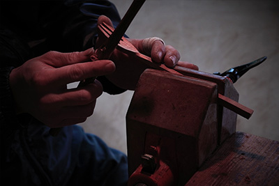 Here he starts to shape the head of a fork, using a sharp blade to perfect the form.