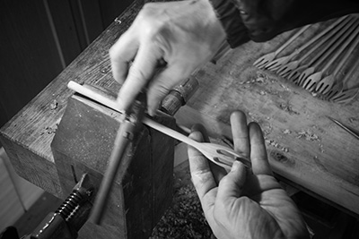 He uses a sharp bladed tool to thin out the handle and create the desired shape.