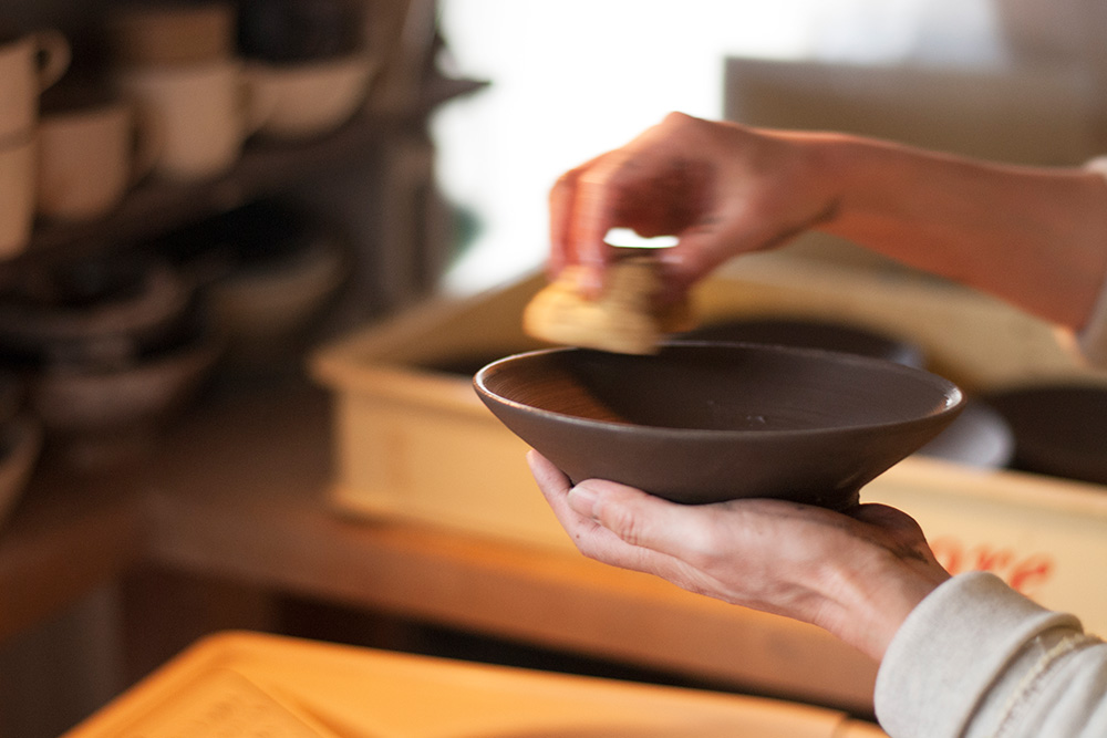 Wiping the edges of a bowl to make sure there are not sharp edges.