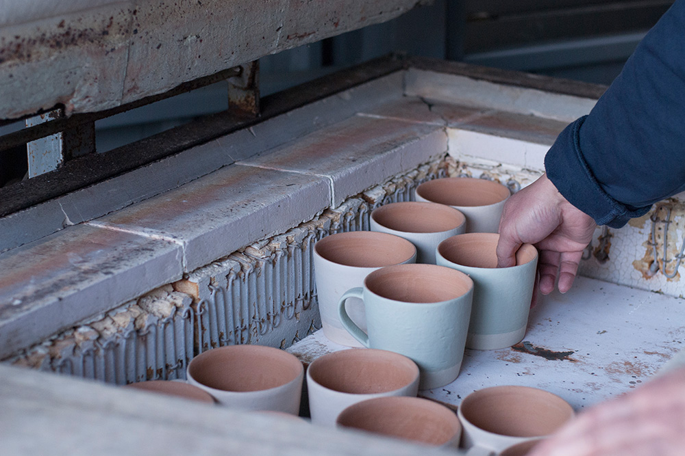 Yuichiro places some mugs in the kiln, these have been glazed and are ready to be fired.