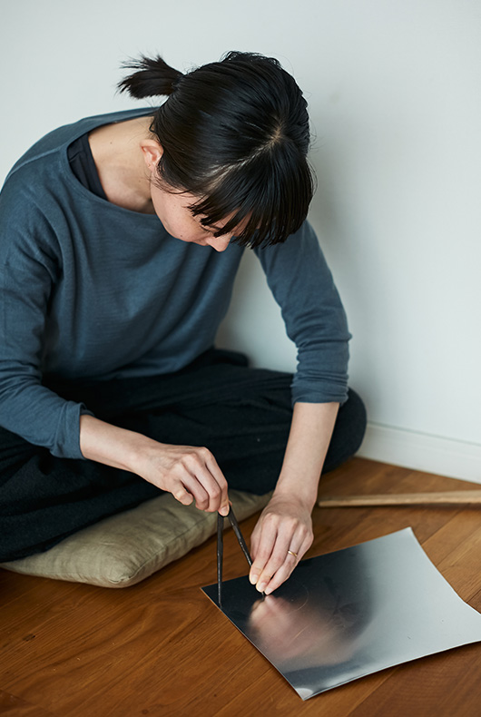 Naho Kamada uses a tool to measure out on a sheet of metal.