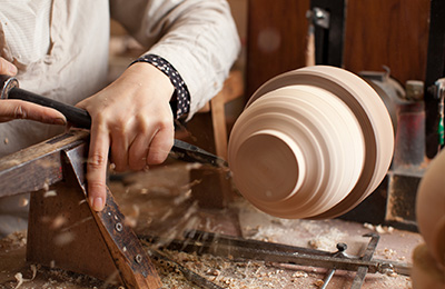 First Maiko takes off the wood around the body of the bowl, removing any excess wood that isn't needed.