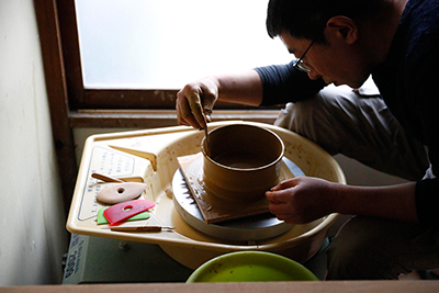Makoto Asebi finds the right height for the plate on the pottery wheel.