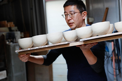 Makoto carrying the work to his pottery kiln.