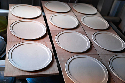 Opening his pottery kiln, a selection of plates and mugs.