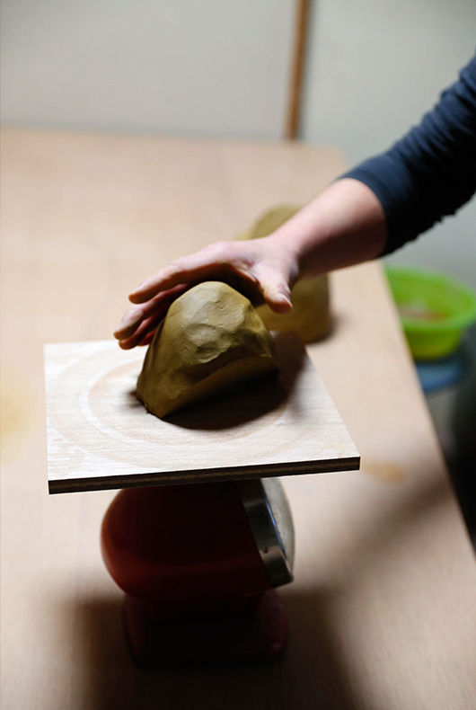 He weighs the clay on his scales to make sure he has the right amount of clay.