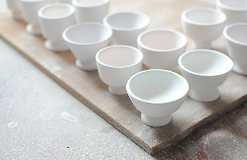 A selection of porcelain pots that have been biscuit fired in her kiln, minimal with striking poise.