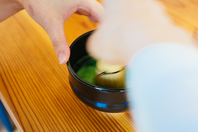 Using a special bamboo whisk called a 'chasen' to mix the matcha powder to make matcha tea.